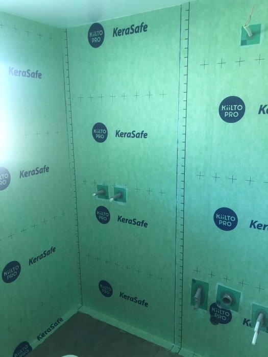 Badrum med nyinstallerat tätskikt på väggarna, med flera genomföringar för VVS och el synliga.