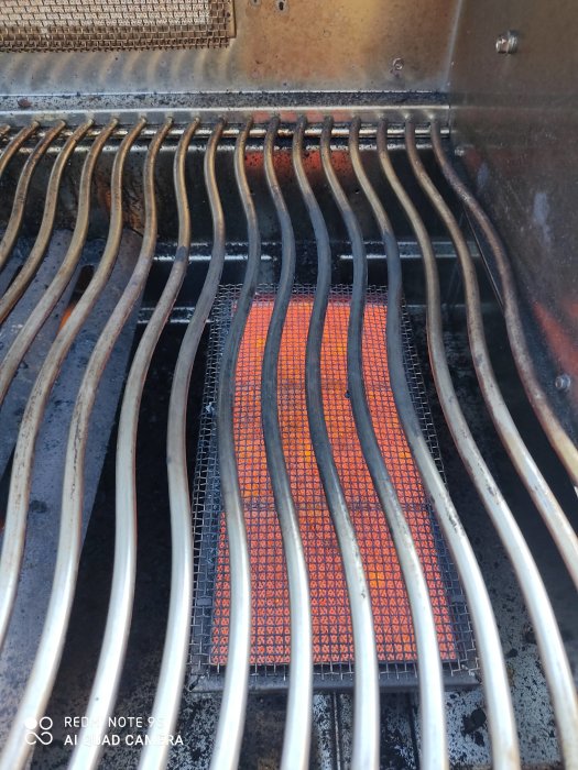 Gasolgrill i drift med synlig temperaturskillnad mellan vanliga brännare och sizzle zone.