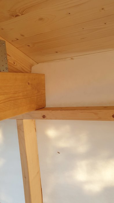 Takstolar och isolering i ett pågående byggprojekt, visar anslutning vid hammarbandet.