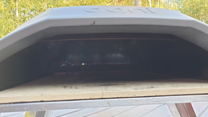 Pizza i vedugn under gräddning, synlig genom ugnens öppning.