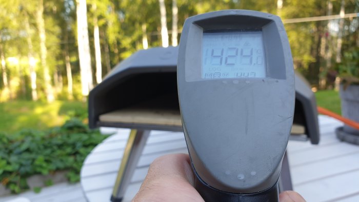 Termometer visar 424 grader Celsius framför en pizzaugn utomhus.