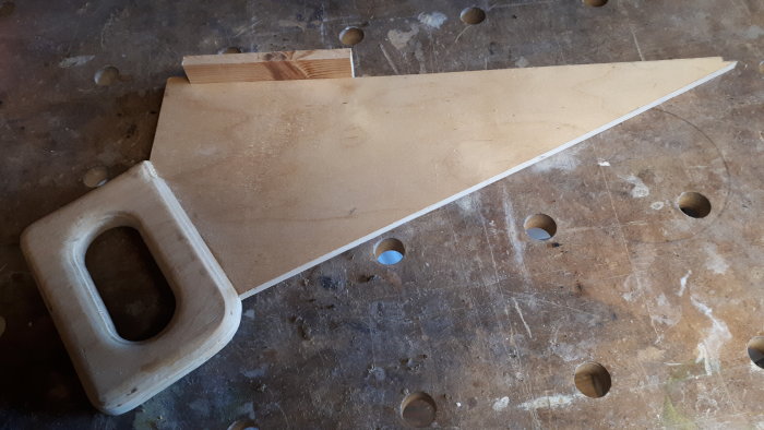 Trätryckstock för säkert handhavande av sågning placerad på en arbetsbänk.