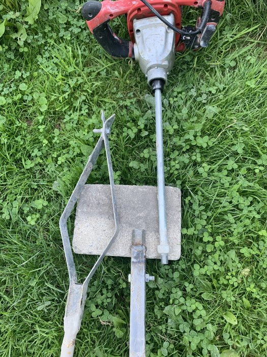 Borrutrustning i gräs med motor, borrstång och anpassad 2 mm galvad plåt för borrning.