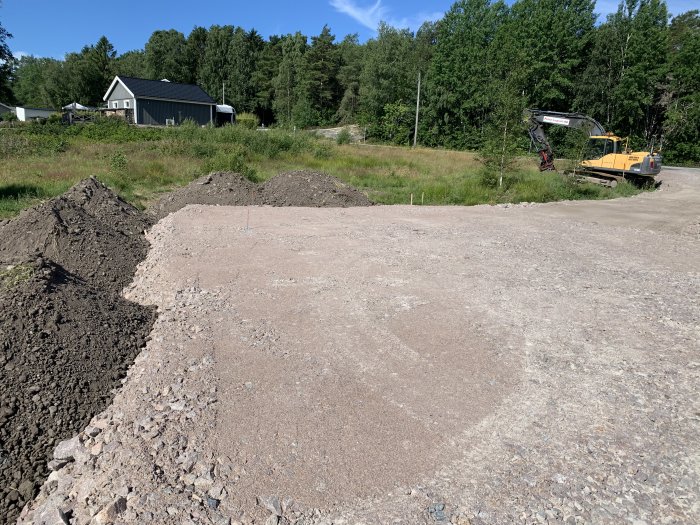 Jordhögar bredvid utgrävd plats för dagvatten och dränering med en grävmaskin i bakgrunden.