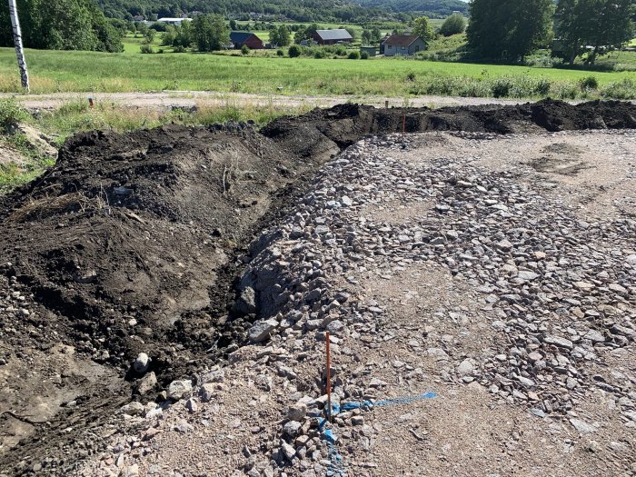 Byggarbetsplats med jord och grushögar redo för dagvattenhantering och dränering.