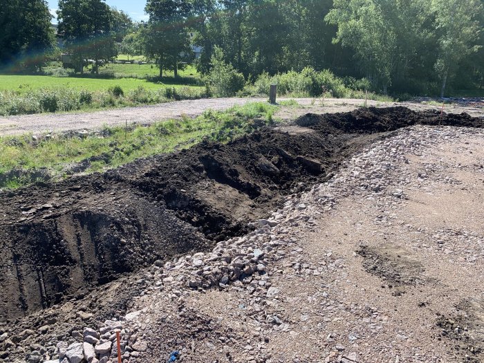 Jordfylle packat längs en byggarbetsplats för att förbereda dränering och dagvattensystem.