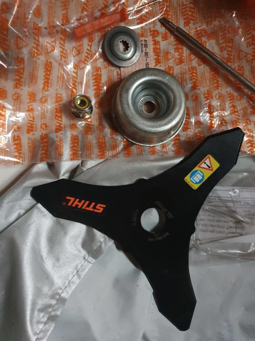Trimmerhuvud och delar på en STIHL FS 240 C inklusive knivblad och monteringskomponenter.