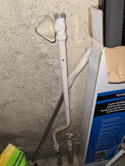 Gammal vitmålad rörgänga på ett uppluggat rörsystem mot en betongvägg, fråga om gängtyp och anslutning.