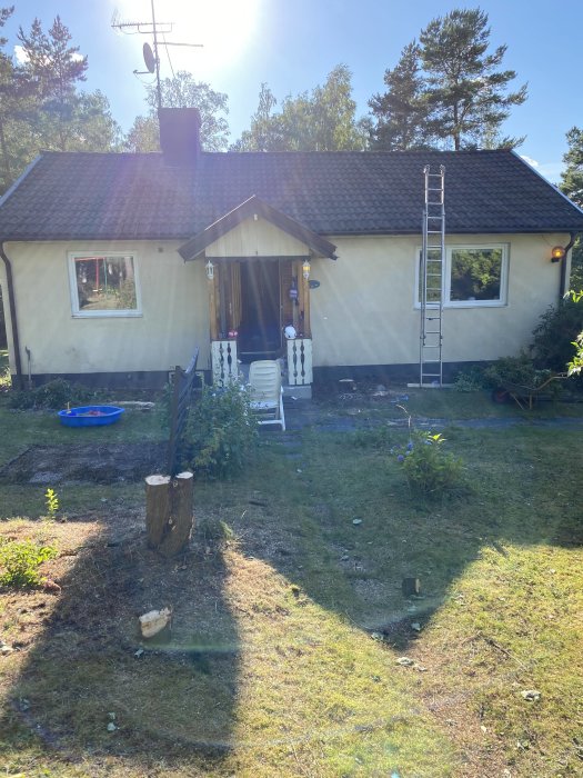 Ett frilagt husområde efter borttagning av thuja, buskar och ogräs, redo för dräneringsarbeten.