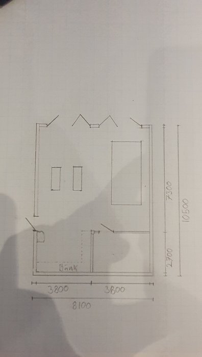 En handritad planritning av ett garage med måttangivelser och markerade dörrar och fönster.