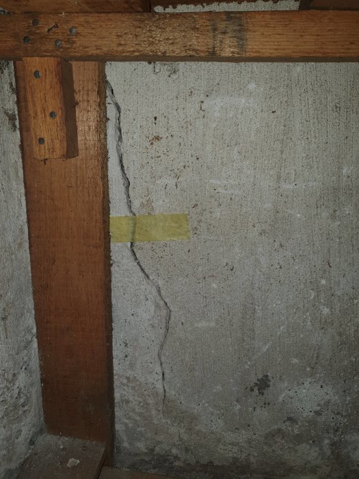 Spricka i källarvägg vid skarven mellan yttervägg och hjärtevägg med tejpmarkering.