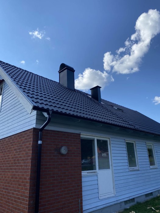 Nytt tak med huvar installerade på skorstenar mot klarblå himmel och soligt väder.