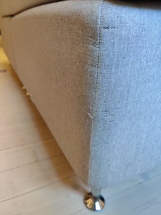 Närbild av en soffas hörn med klös-skador på tyget.