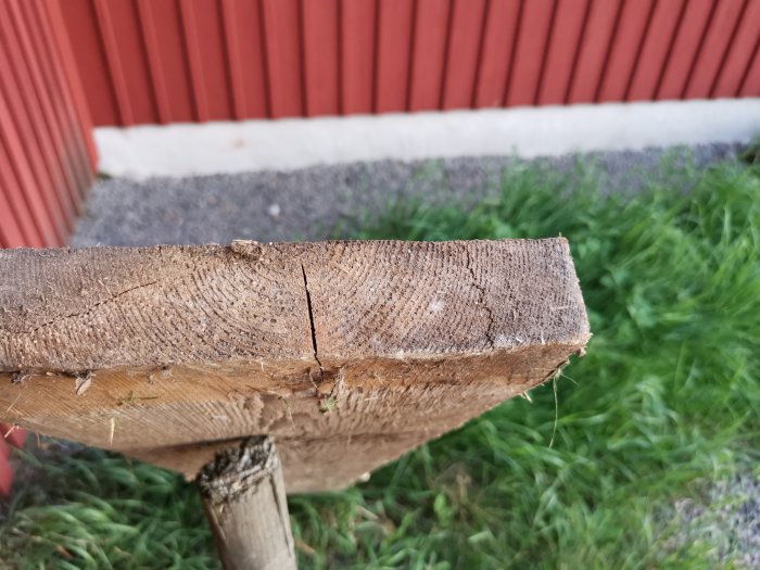 Närbild på en avslöjad ände av en gammal golvbräda som visar träets ådring och struktur.