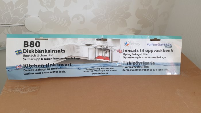 Förpackning av diskbänksinsats från Tollco med illustration av produktens placering under en diskbänk.