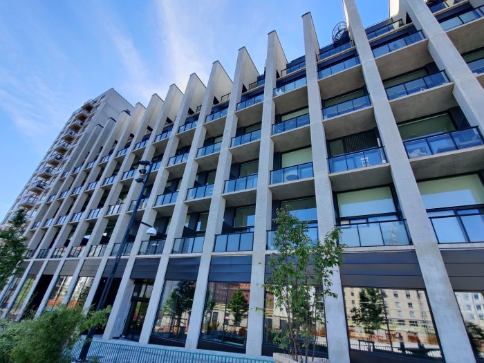 Moderna bostadshus med distinkta betongpelare i Solna, nära Vasastan, under en klarblå himmel.