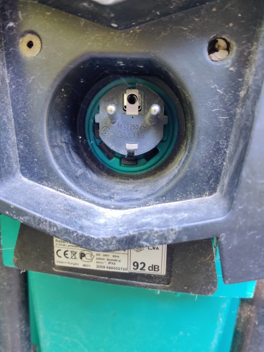 En närbild av ett eluttag på en Bosch kompostmaskin AXT 22 D, där uttaget sitter fast och lite snett.