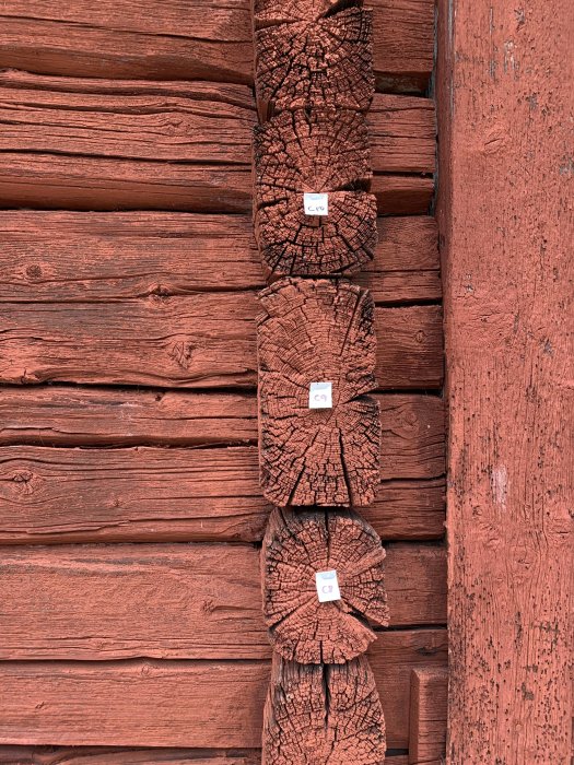 Märkt gammalt timmer med nummerlappar för återuppbyggnad av lada.