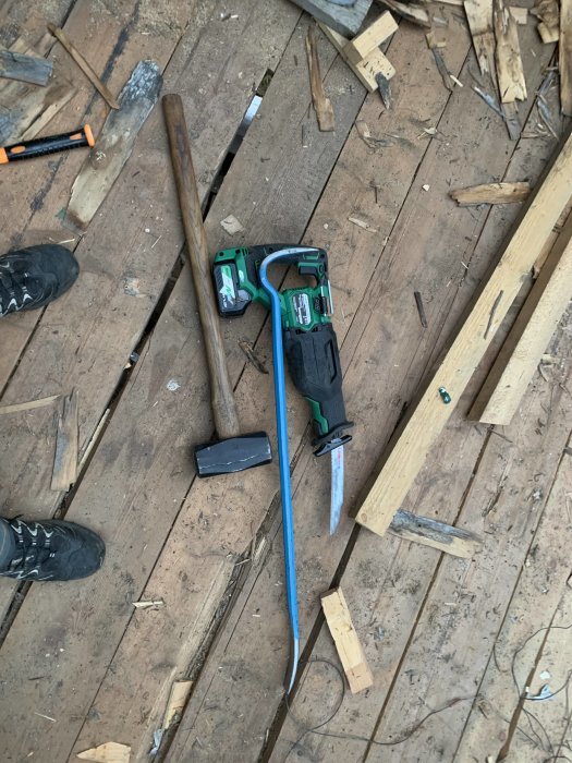 Verktyg och trärester på golvet i en timmerlada under renovering.