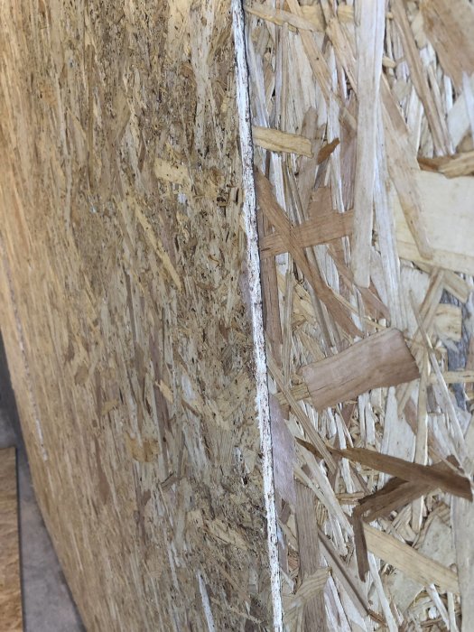 OSB-plater montert på en vegg med synlig glippe mellom platene, viser skjøtproblematikk i garasjebyggeprosjekt.