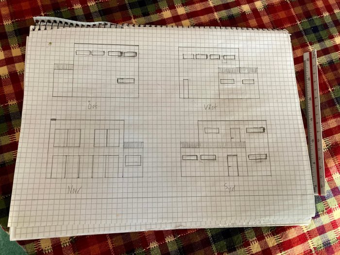Handritad skiss av husplanlösning på rutat papper med kompassriktning och måttangivelser.