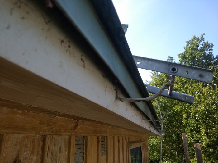 Lös takfotsbräda och hängränna som sackat på ett hus, med synliga skruvar och spikar.