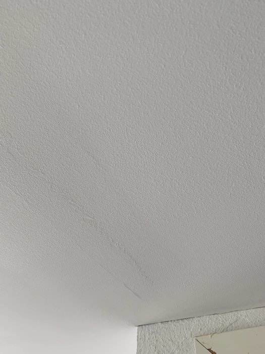 Glansigt våtrumsmembran på gipstak i badrum jämfört med matt yta utanför.