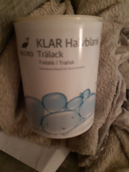 En burk Alcro klarlack för inomhusträ på en handduk, suddig.