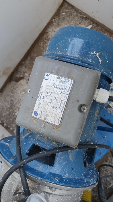 Blå Foras JXF 106 vattenpump med teknisk informationsetikett, täckt av sågspån.