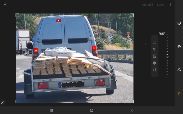 Lastbil med öppen baklucka som transporterar trävirke säkrat med betongsäckar.