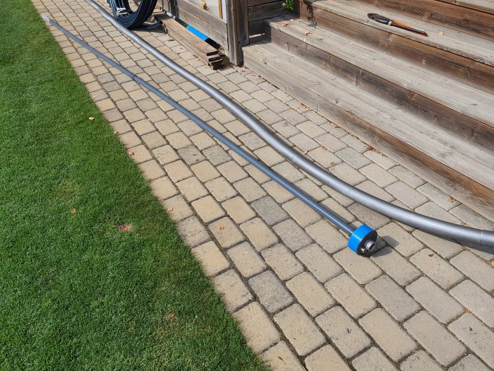 PVC-rör och komponenter för brunnsinstallation nära en trätrall och stenläggning.