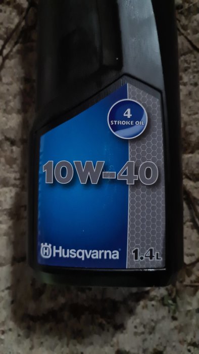 Flaska med 10W-40 4-taktsolja från Husqvarna på 1,4 liter.
