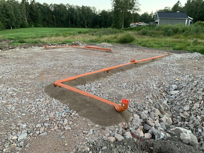 Installation av dagvattenrör med grusomgivning på en byggarbetsplats.