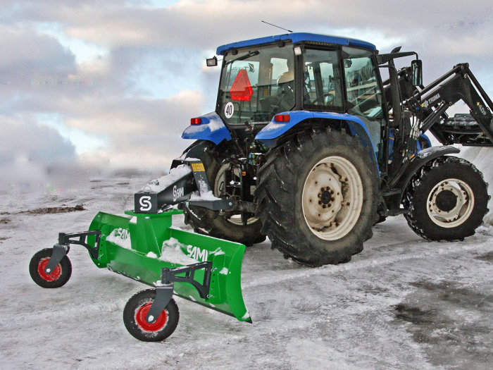 Blå traktor med svängbart snöblad framtill på ett vinterlandskap.