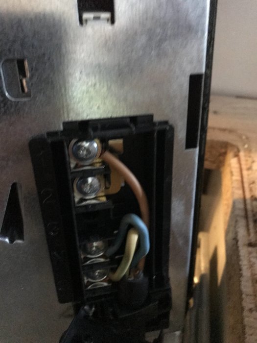 Elektrisk spishälls anslutningsplint med tre kablar och skruvanslutningar.