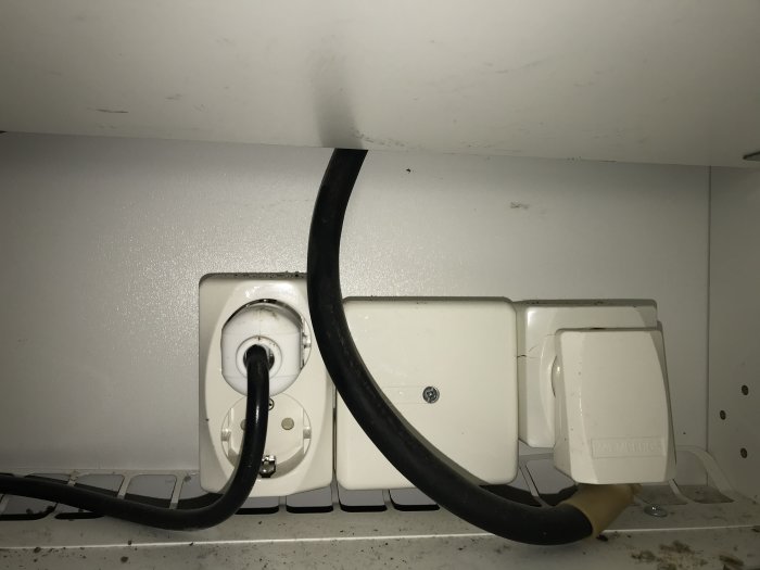 Eluttag med ansluten tjock svart kabel och vit kabel i kök, används för spis och varmluftsugn.