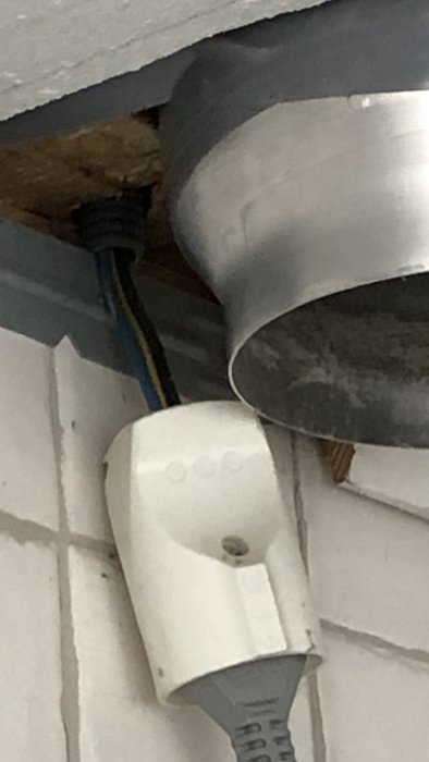 Elkablar inkopplade på ett osäkert sätt ovanför en köksfläkt, mot bakgrund av kakel och trä.