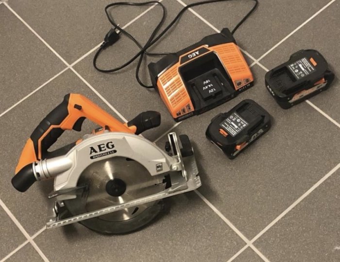 AEG 18v klyvsåg med borstlös motor, två batterier och laddare på ett klinkergolv.