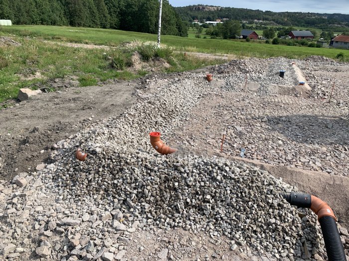 Nyjusterat dräneringsrör med makadam under dagvattnet mot samlingsbrunn på en byggarbetsplats.