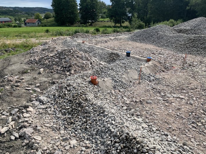 Grus och makadam på byggarbetsplats med synlig dränering och samlingsbrunn under dagvatten.