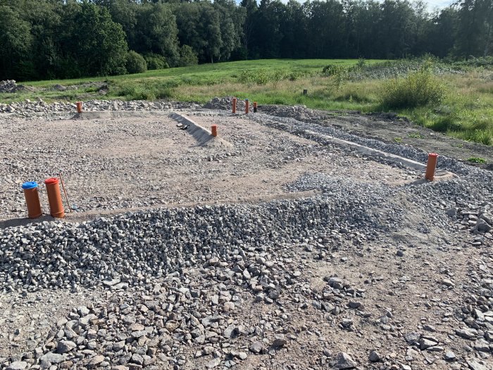 Grusad byggarbetsplats med markerade rörbitar för dagvattenanslutningar.