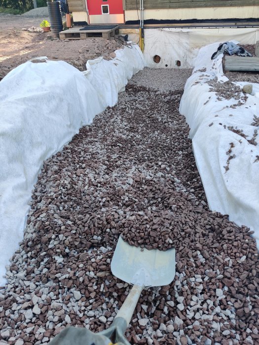 Grusad grund med täckt kulvert och avloppsledningar förbereda för isolering vid byggprojekt.