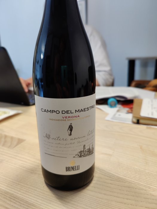 Flaska Campo Del Maestro Verona på ett bord framför oskarp kontorsbakgrund.