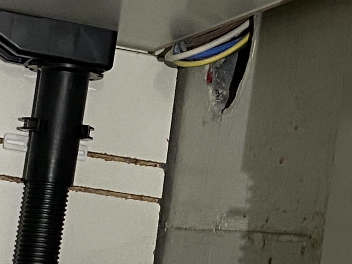 Elinstallation med osäker eldragning och synliga kablar utan isolering bakom köksskåp.