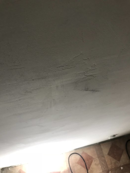 Vägg med ojämnheter och små hål som kan behöva spacklas och slippas innan målning.