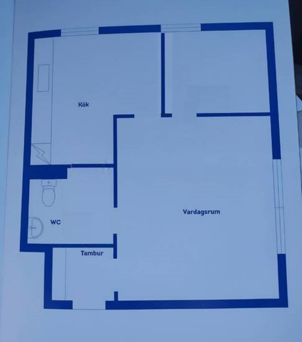 Schematisk ritning av en lägenhetsplanlösning, med kök, WC, tambur och vardagsrum märkta.