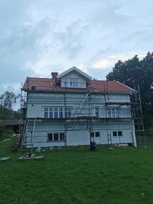 Hus under renovering med ställningar och nyklädd kupol på baksidan mot en molnig himmel.