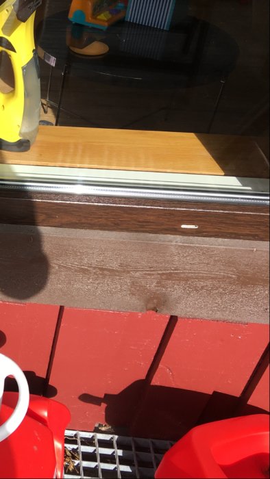 Fönster utan bleck visar fönsterkarm, tröskel och leksaker innanför ett soligt fönster.