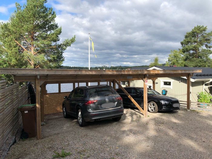 Carport med tak, två bilar parkerade, inga synliga lampor eller ledslingor.