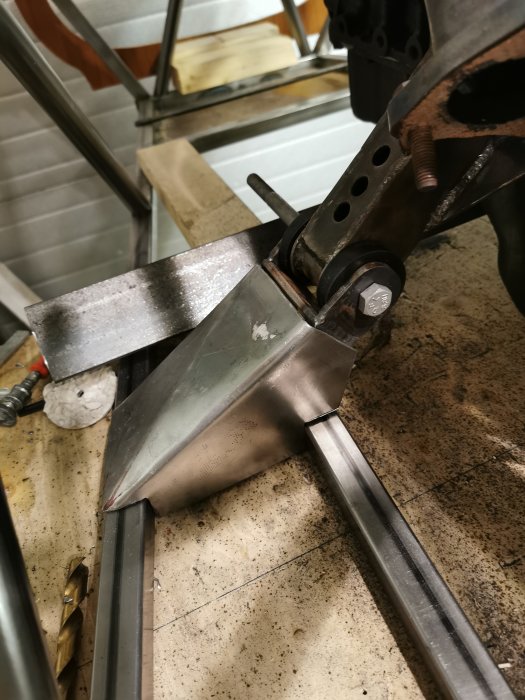 Metallkomponent fastspänd i skruvstycke på verkstadsbänk som visar byggprojektets framsteg.